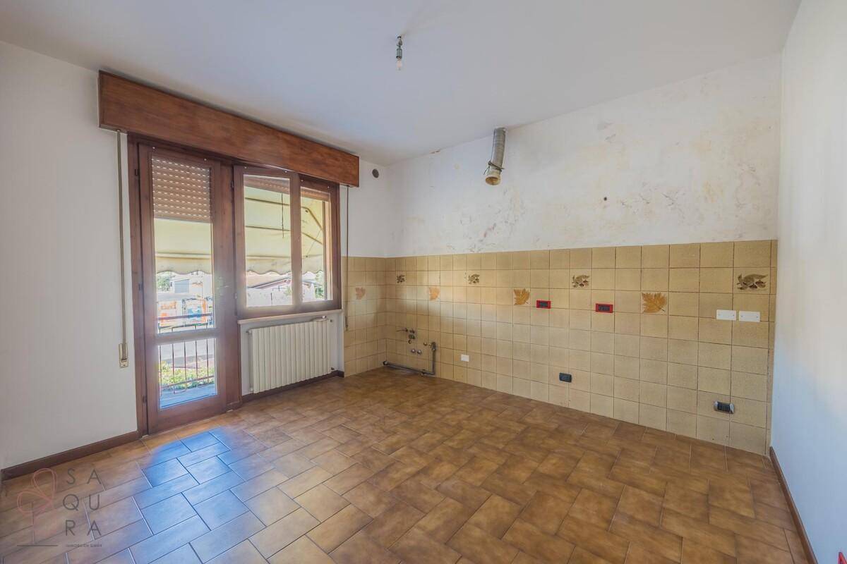Leere Küche mit Fliesenboden und teilweise gefliesten Wänden, bereit für die Installation einer neuen Küche.