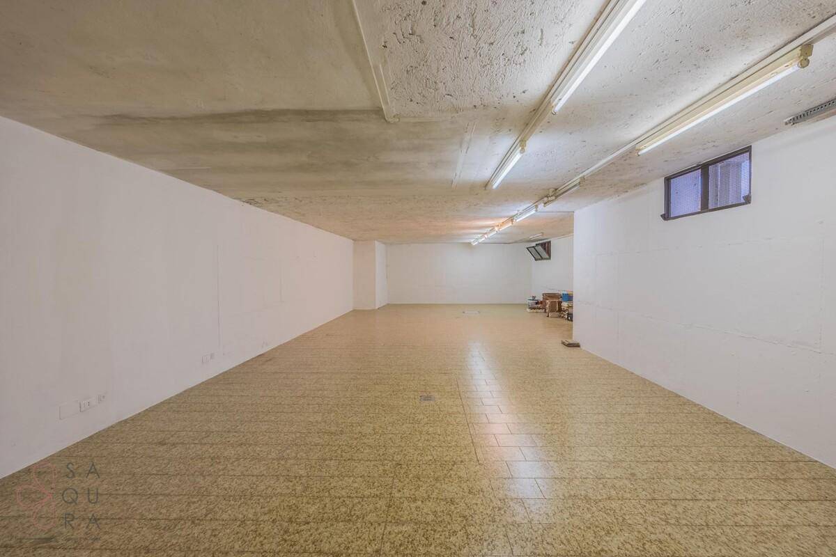 Großer, leerer Kellerraum mit Fliesenboden, weißen Wänden und sichtbarer Betondecke, ideal als Lagerfläche.