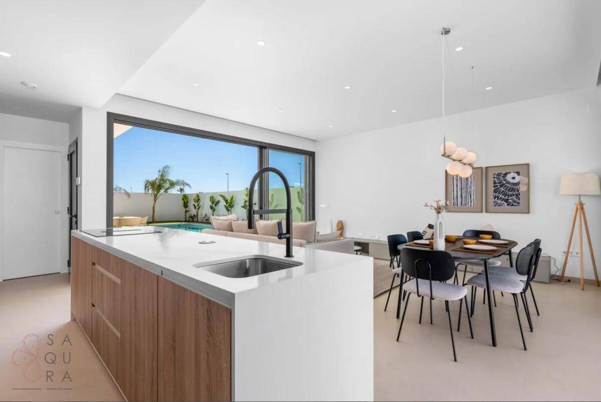 Moderne Küche mit Kochinsel und Essbereich, offen zum Wohnzimmer mit Poolblick.
