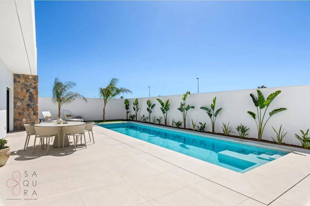 Langer Swimmingpool mit angrenzender Terrasse und mediterraner Bepflanzung unter strahlendem Himmel.