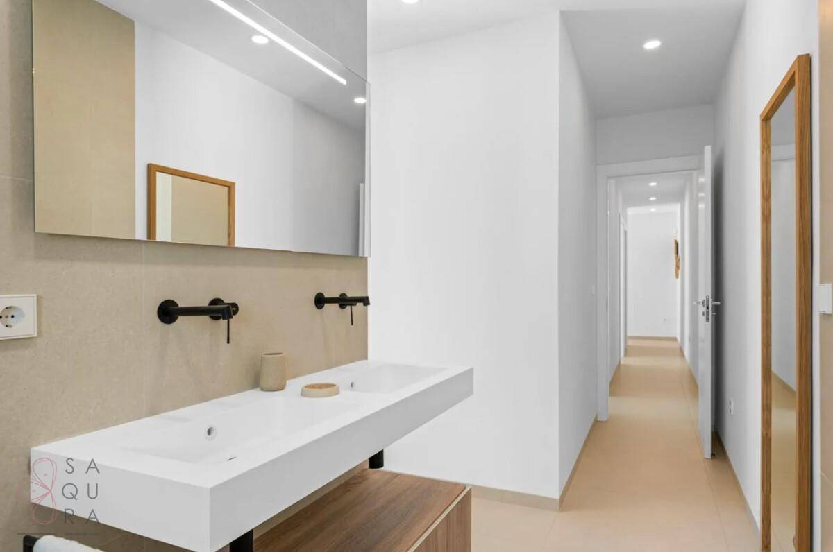 Modernes Badezimmer mit Doppelwaschbecken und schlichtem Design, angrenzend an einen Flur.