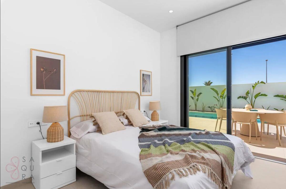 Freundliches Schlafzimmer mit Rattan-Kopfteil und Blick auf die sonnige Poolterrasse.