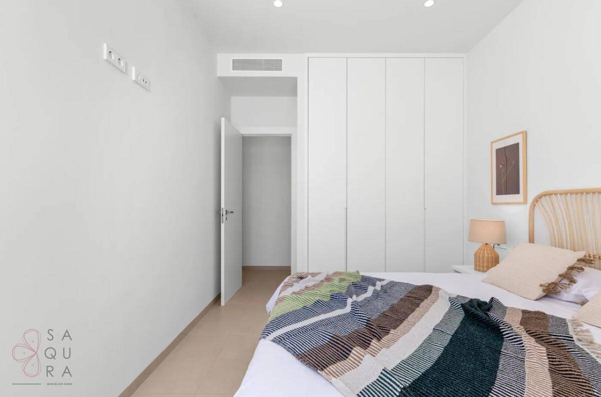 Modernes Schlafzimmer mit integrierten weißen Kleiderschränken und schlichter Einrichtung.