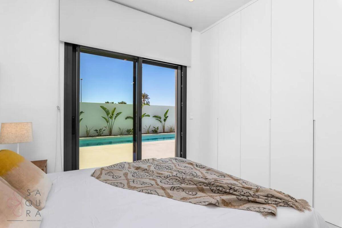 Helles Schlafzimmer mit großen Schiebetüren zum Pool und integrierten Kleiderschränken.