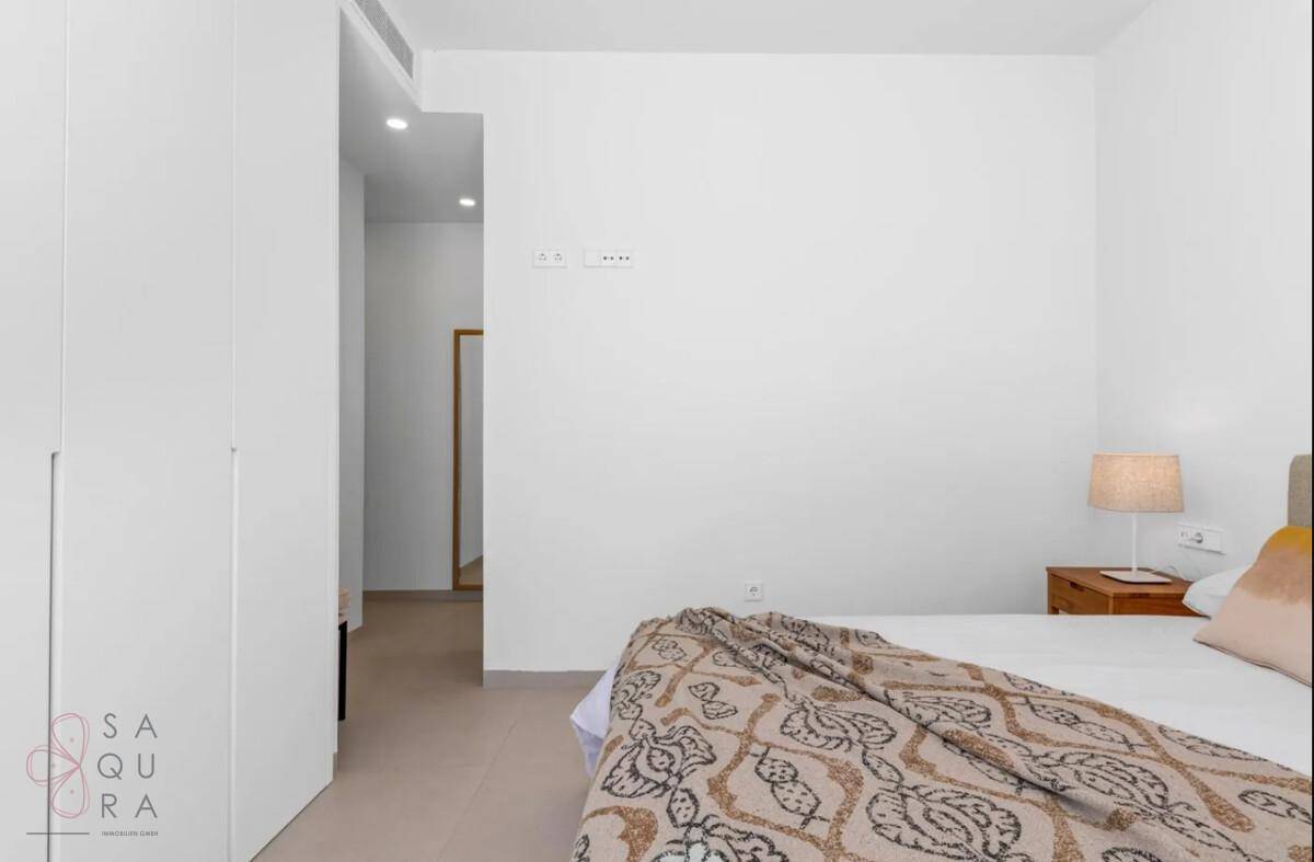 Modernes Schlafzimmer mit weißer Einrichtung und Zugang zu einem hellen Flur.