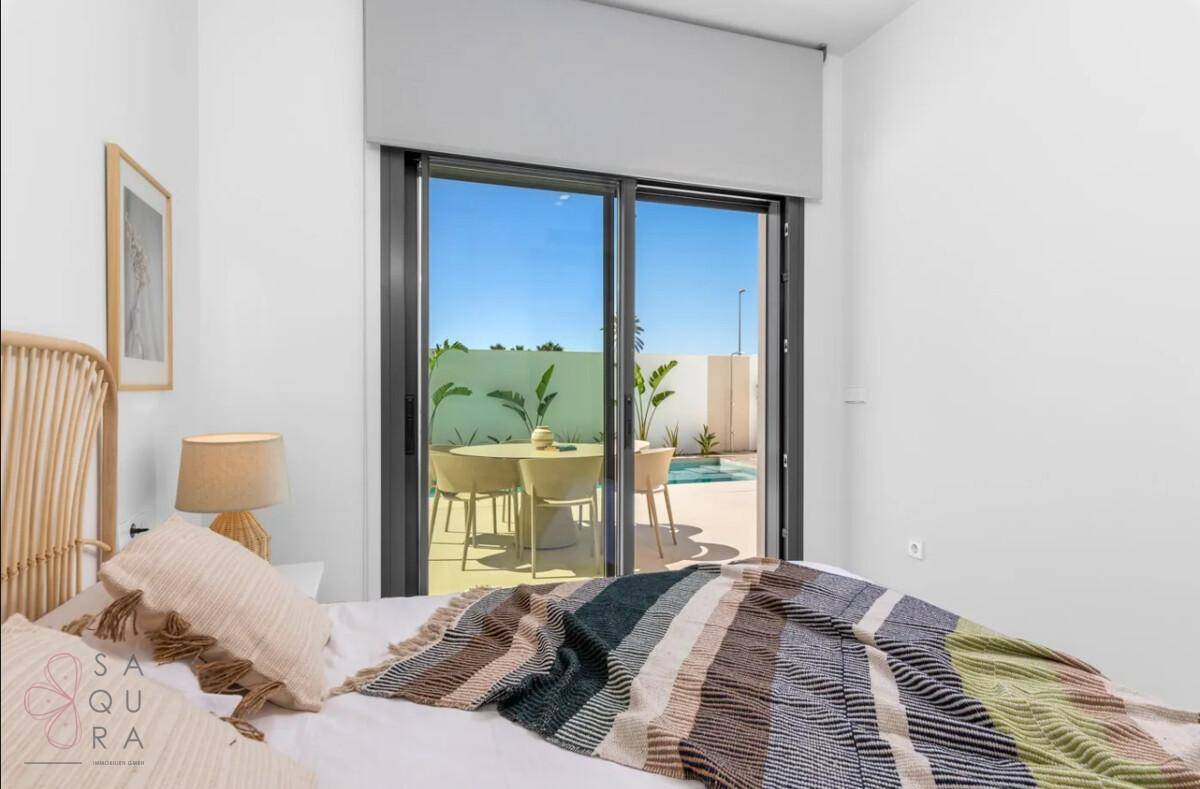 Helles Schlafzimmer mit großen Schiebetüren, die den Blick auf den Außenbereich freigeben.
