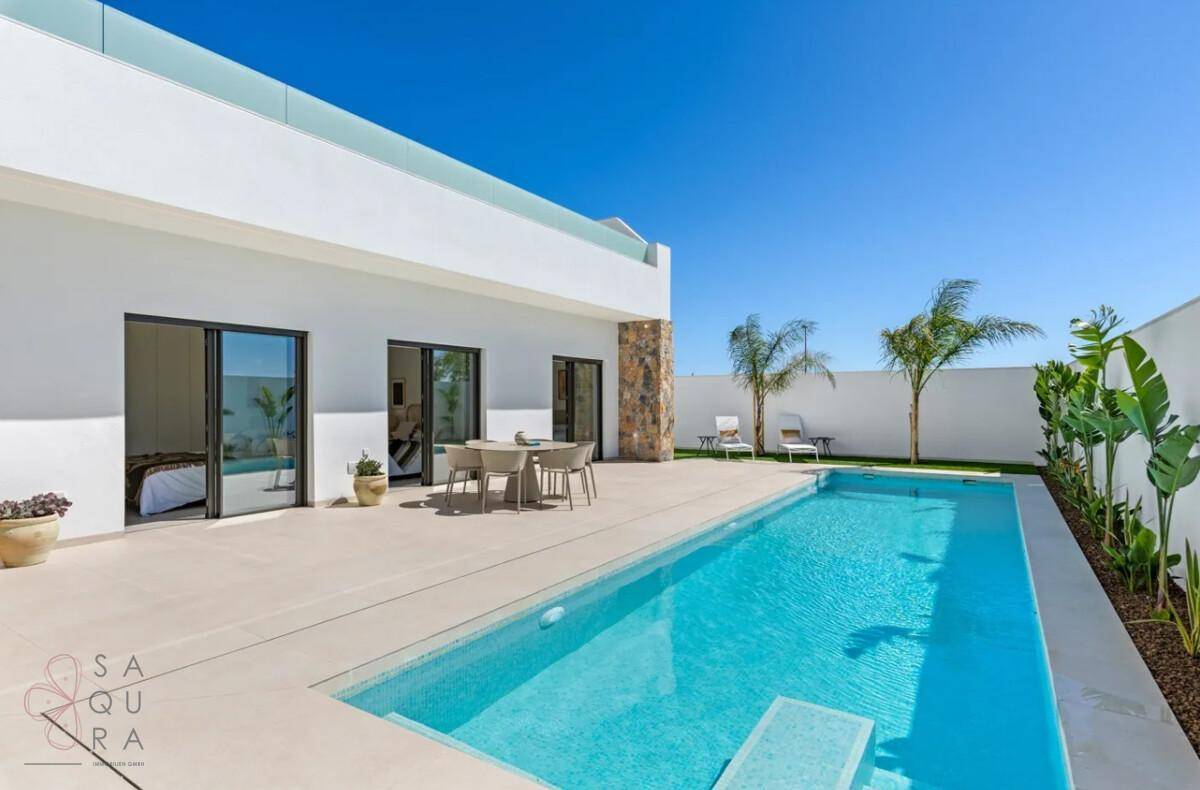 Moderne Villa mit großem Pool, Sonnenterrasse und Liegestühlen unter blauem Himmel.