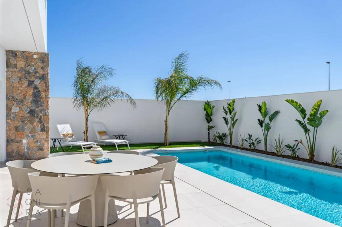 Moderner Außenbereich mit privatem Pool, Essbereich und Liegestühlen unter Palmen.