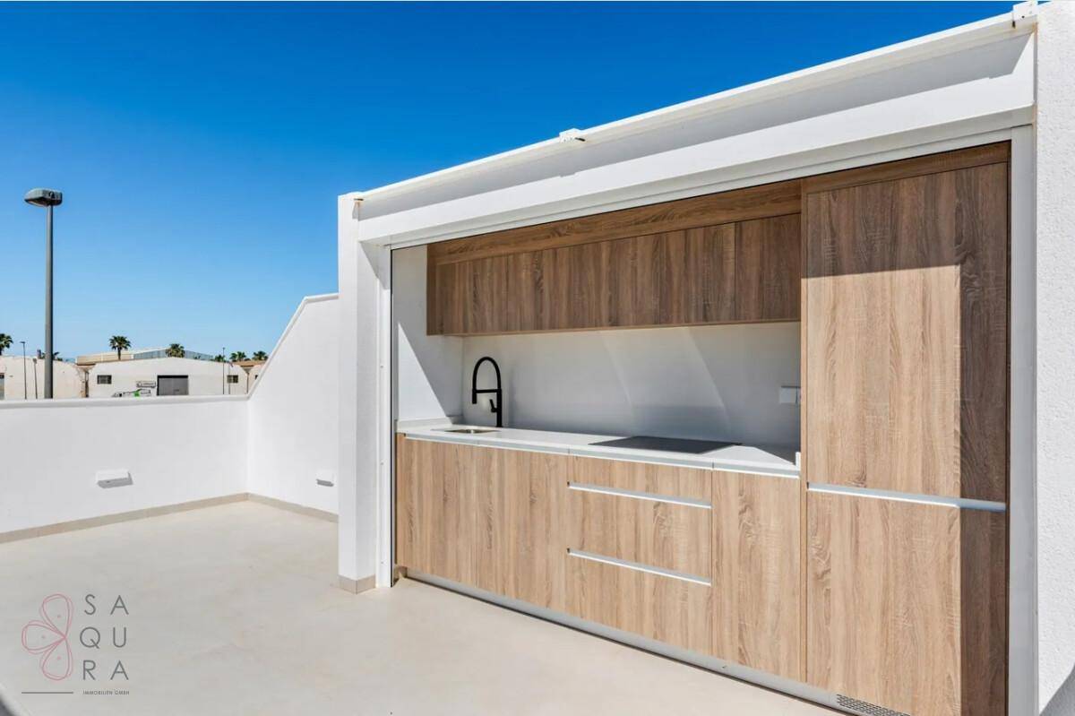 Detailansicht der modernen Außenküche auf der Dachterrasse mit Holzschränken und Spülbecken.