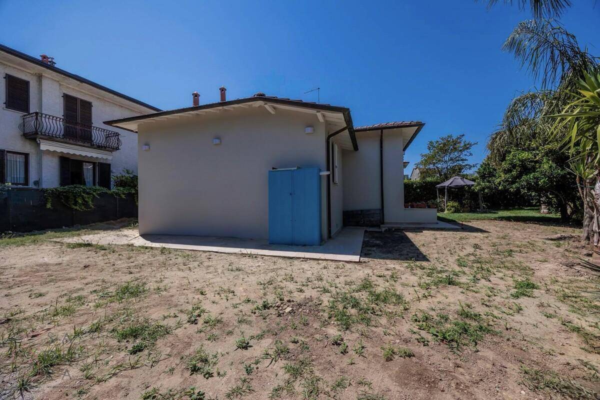 Rückansicht des Hauses mit unfertigem Gartenbereich und einem blauen Schrank an der Wand.