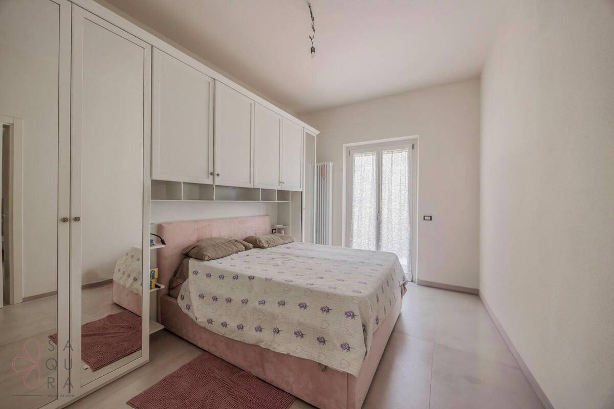Helles Schlafzimmer mit Einbauschränken über dem Bett und Zugang zu einem Balkon oder Fenster.