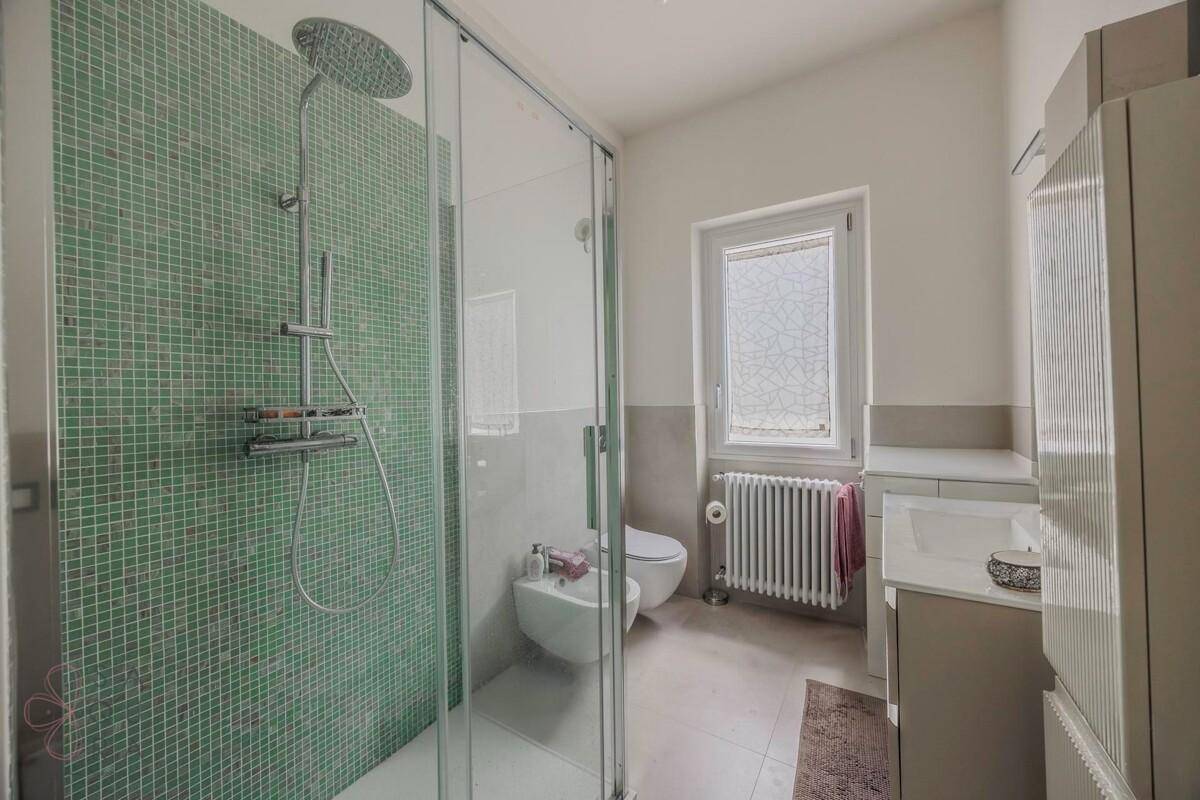 Modernes Badezimmer mit großer Duschkabine, Bidet und Fenster.