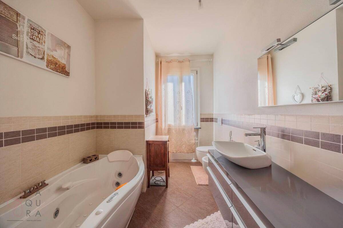Modernes Badezimmer mit Whirlpool-Badewanne, Doppelwaschbecken und Fenster.