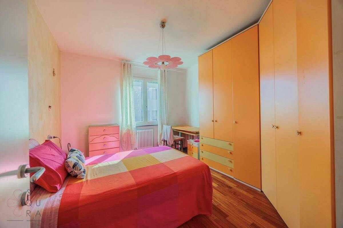 Kinderzimmer mit farbenfroher Bettwäsche, Holzfußboden und gelben Einbauschränken.