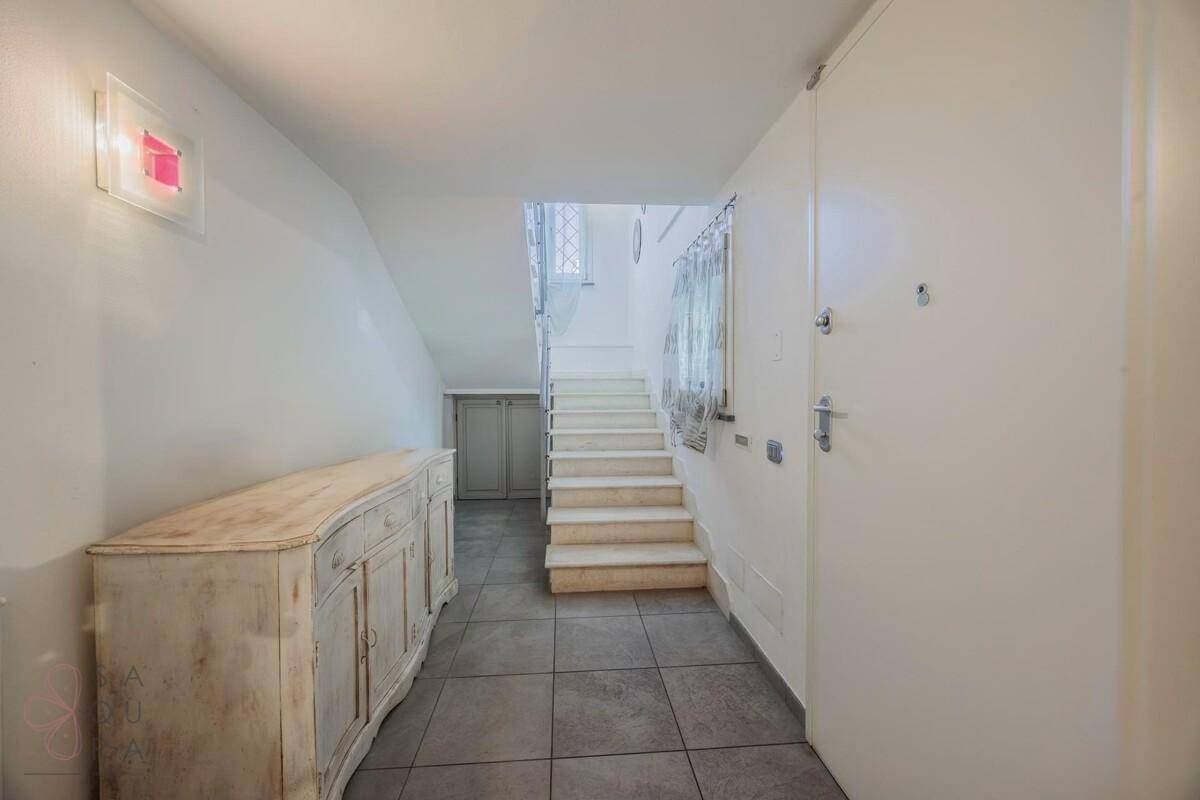 Eingangsbereich mit Fliesenboden, Treppe zum Obergeschoss und antiker Kommode.