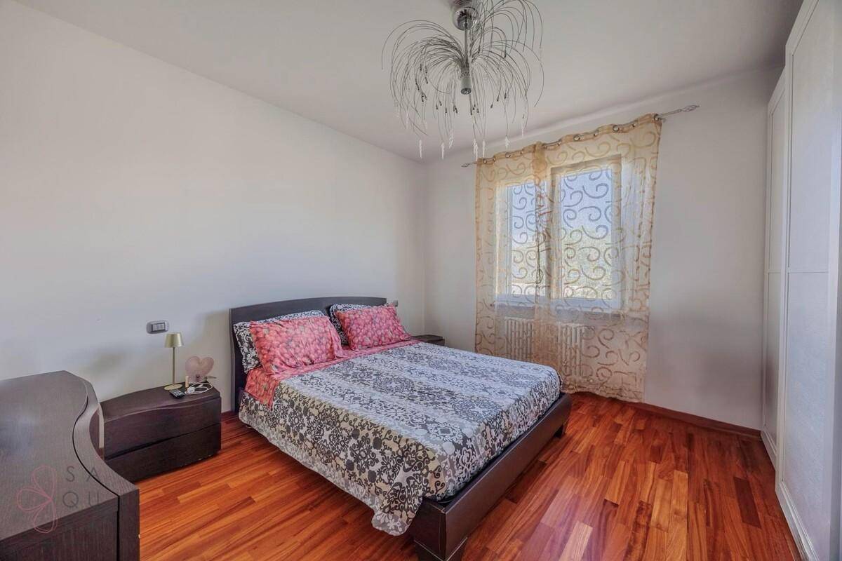 Schlafzimmer mit Holzfußboden, Doppelbett und dekorativem Kronleuchter.