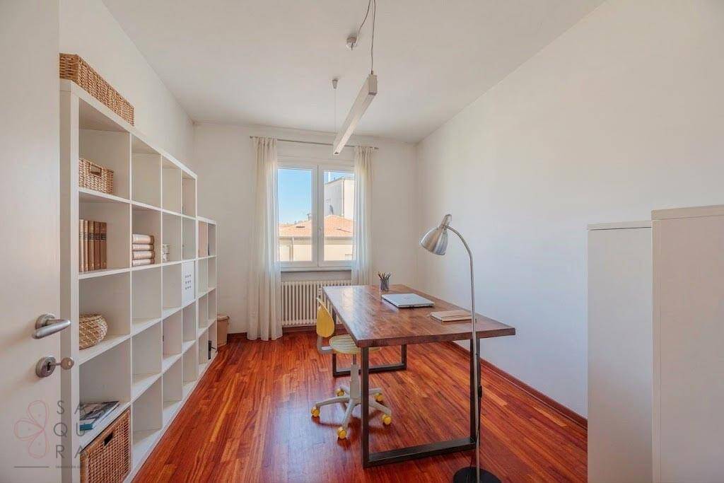 Helles Arbeitszimmer mit Holzfußboden, großem Schreibtisch und Bücherregal.