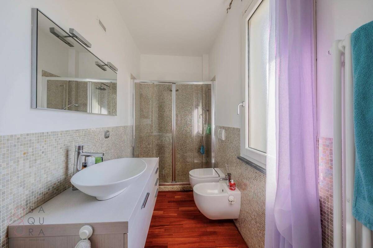 Modernes Badezimmer mit begehbarer Dusche, Bidet und Holzfußboden.