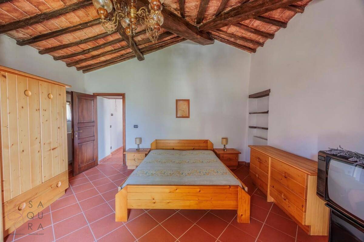Helles Schlafzimmer mit Holzbalkendecke, Terrakottafliesen und traditionellen Holzmöbeln.