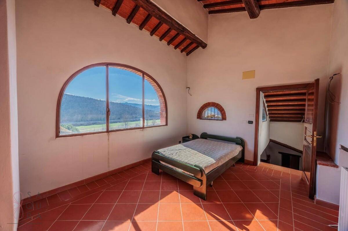 Schlafzimmer mit großem Rundbogenfenster, das einen weiten Blick auf die Landschaft bietet.