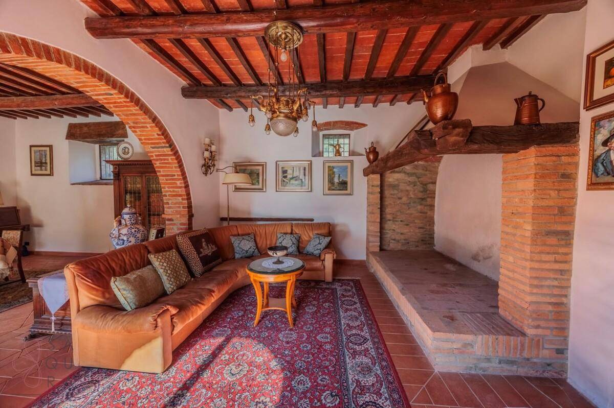 Rustikales Wohnzimmer mit großem Kamin, Holzbalkendecke und bequemen Sofas für entspannte Abende.