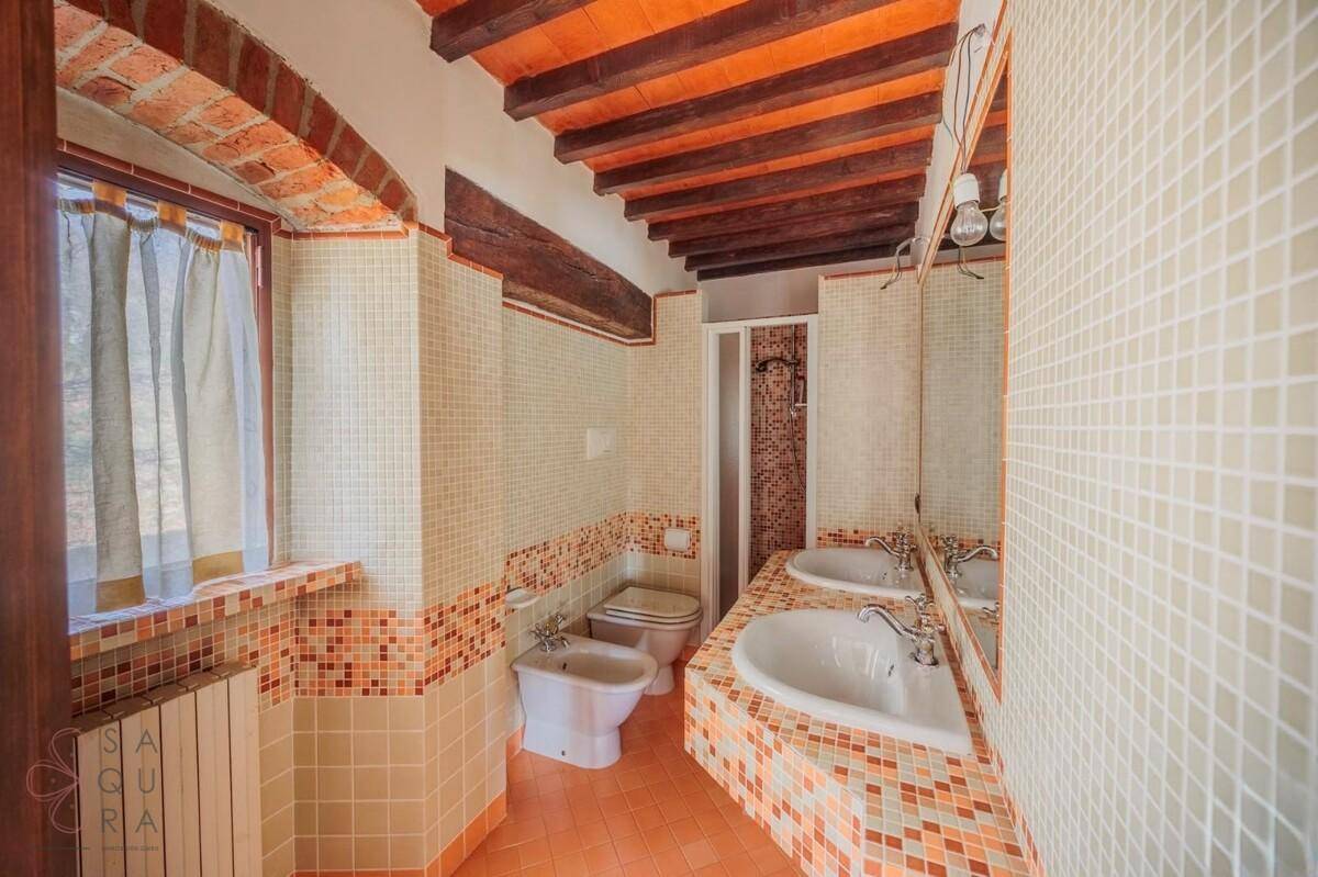 Traditionelles Badezimmer mit Doppelwaschbecken, Bidet und Duschkabine, gefliest in warmen Farbtönen.