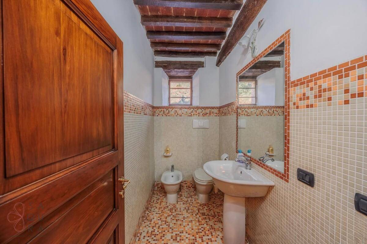 Kleines Gäste-WC mit Waschbecken, Toilette und Bidet, gefliest in traditionellem Stil.