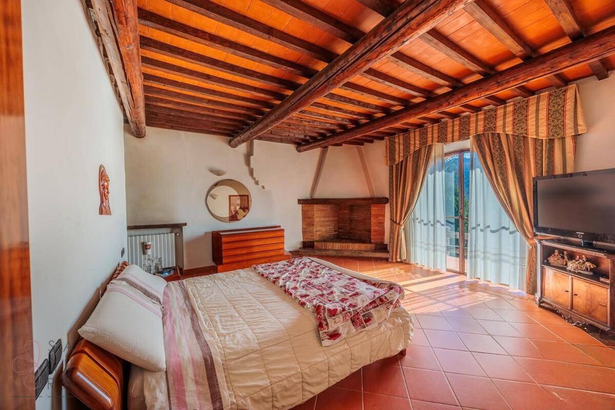 Schlafzimmer mit Kamin, Holzbalkendecke und Zugang zu einem Balkon oder einer Terrasse.
