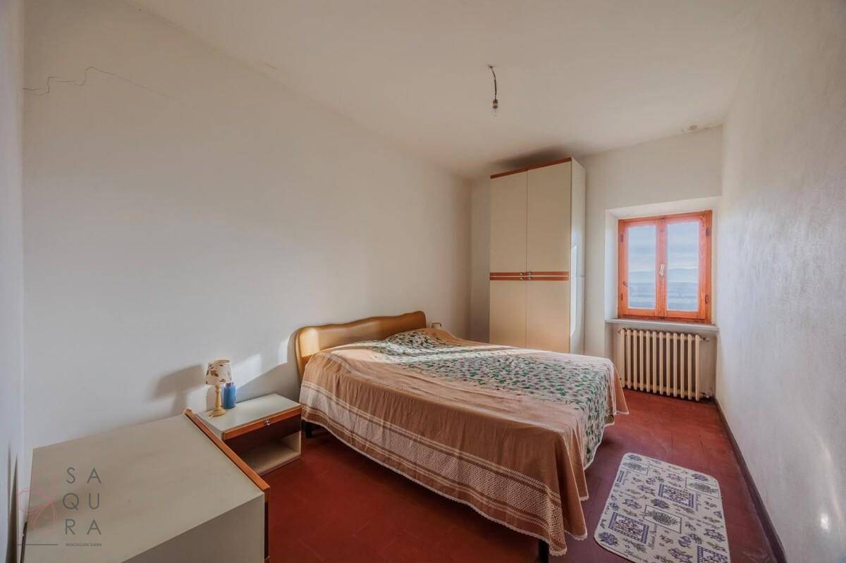 Helles Schlafzimmer mit einfacher Einrichtung, Terrakottaboden und einem Fenster mit Ausblick.