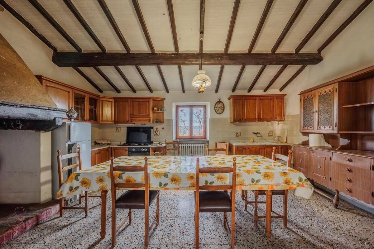 Geräumige traditionelle Küche mit Holzeinbauten, großem Esstisch und Terrazzoboden.