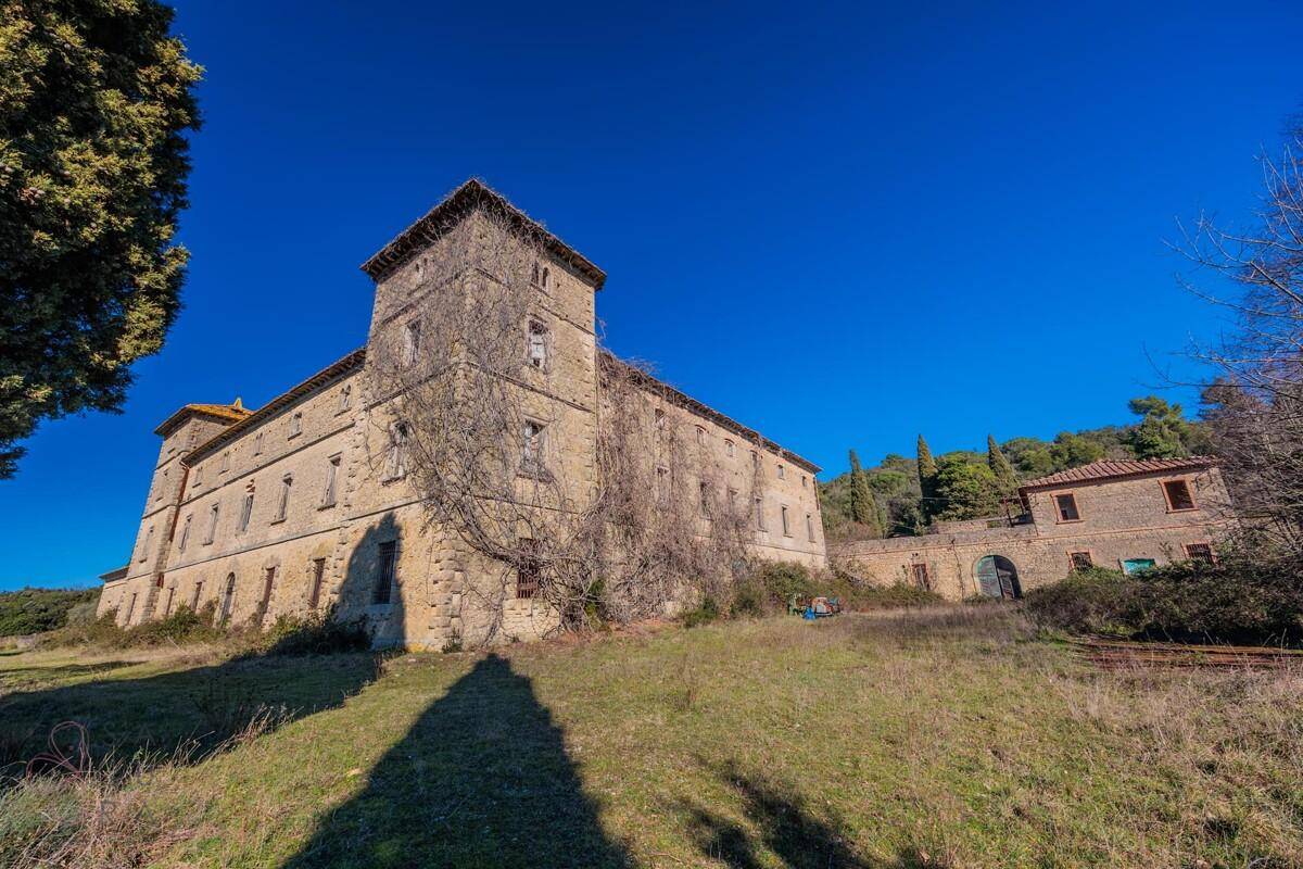 Historisches Gebäude mit bewachsener Steinfassade und einem angrenzenden Nebengebäude in der Natur.