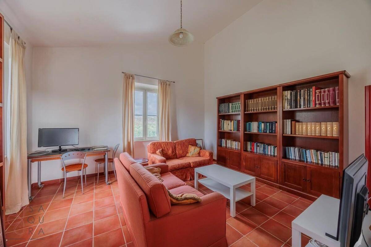 Gemütliches Wohnzimmer mit Terrakottafliesen, zwei Sofas und einem großen Bücherregal.