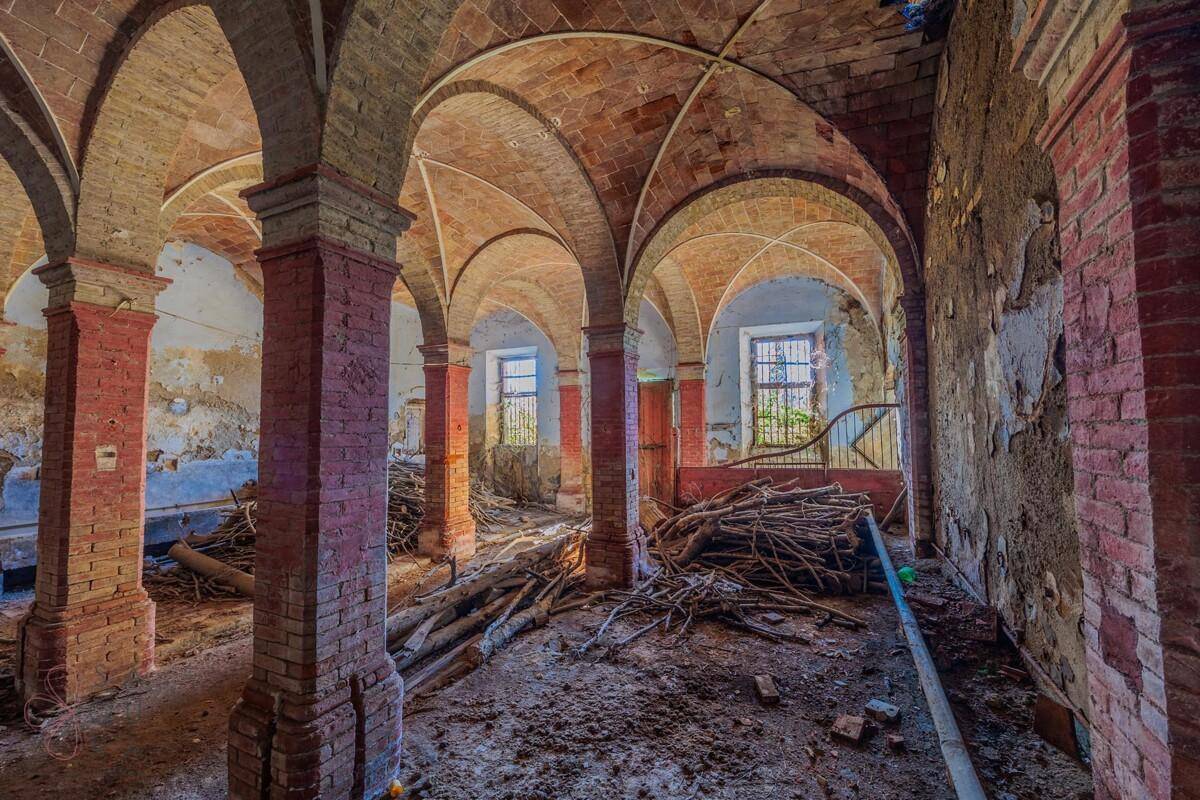 Historischer Innenraum mit beeindruckenden Gewölbedecken aus Ziegeln und Säulen, in Verfallszustand.