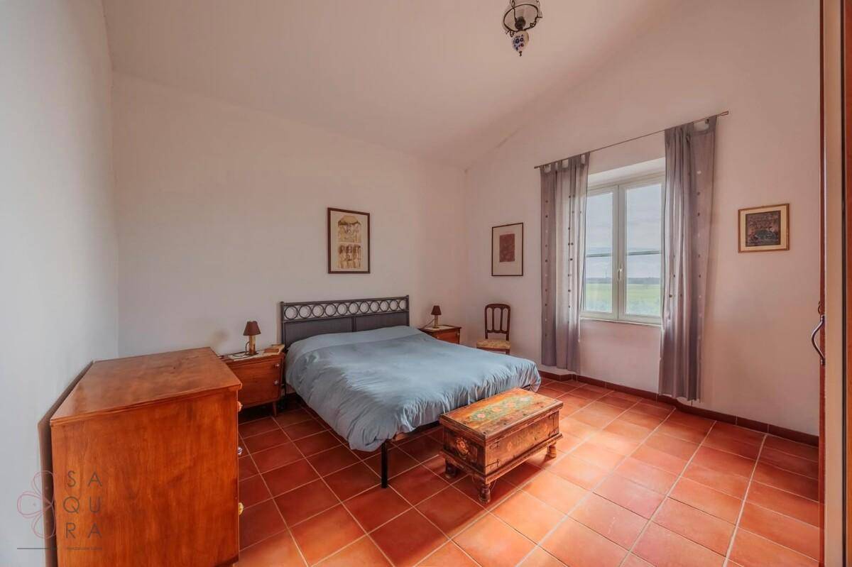 Schlafzimmer mit Terrakottafliesen, Doppelbett und rustikalen Holzmöbeln.