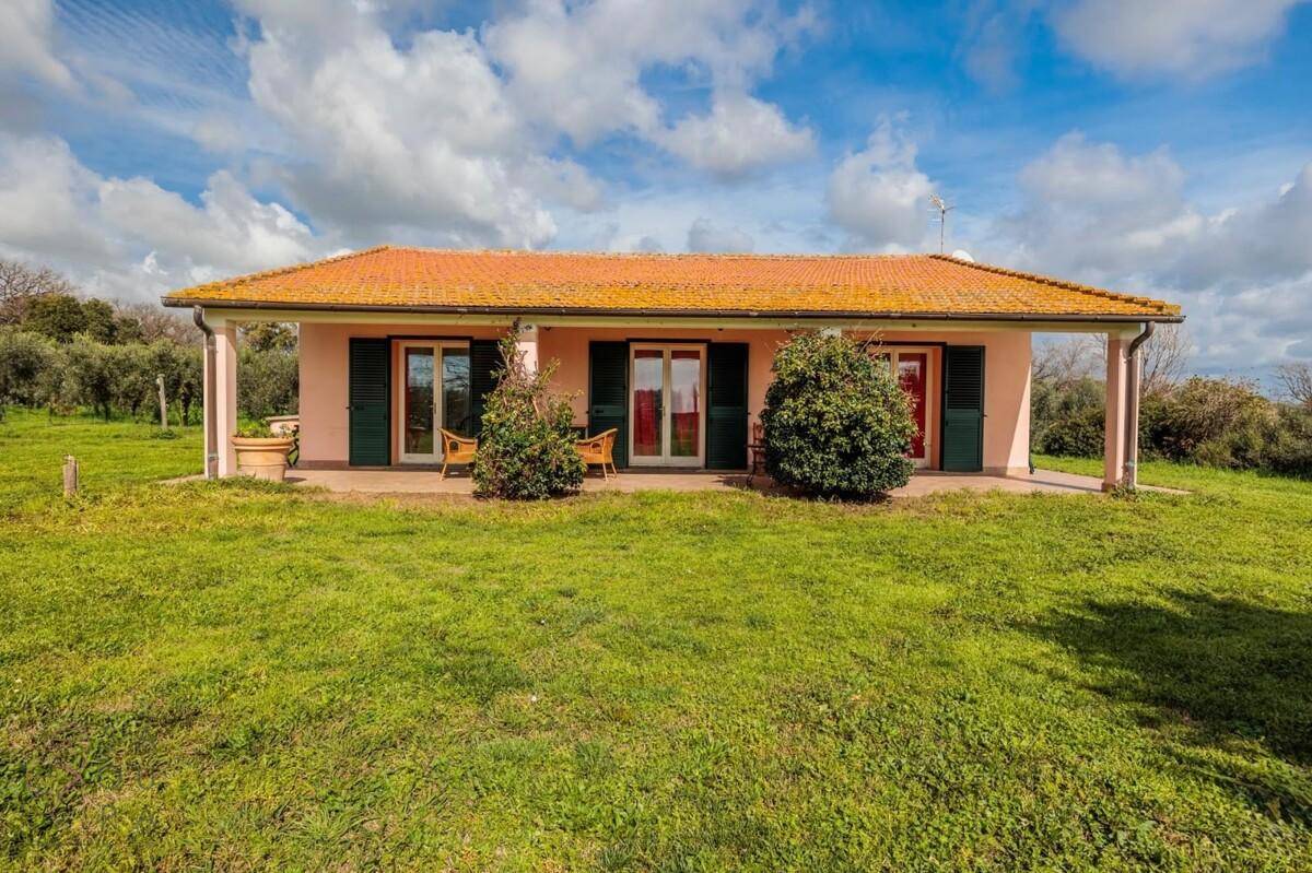 Ansicht des zweiten Landhauses mit rosa Fassade, grünen Fensterläden und überdachter Terrasse.