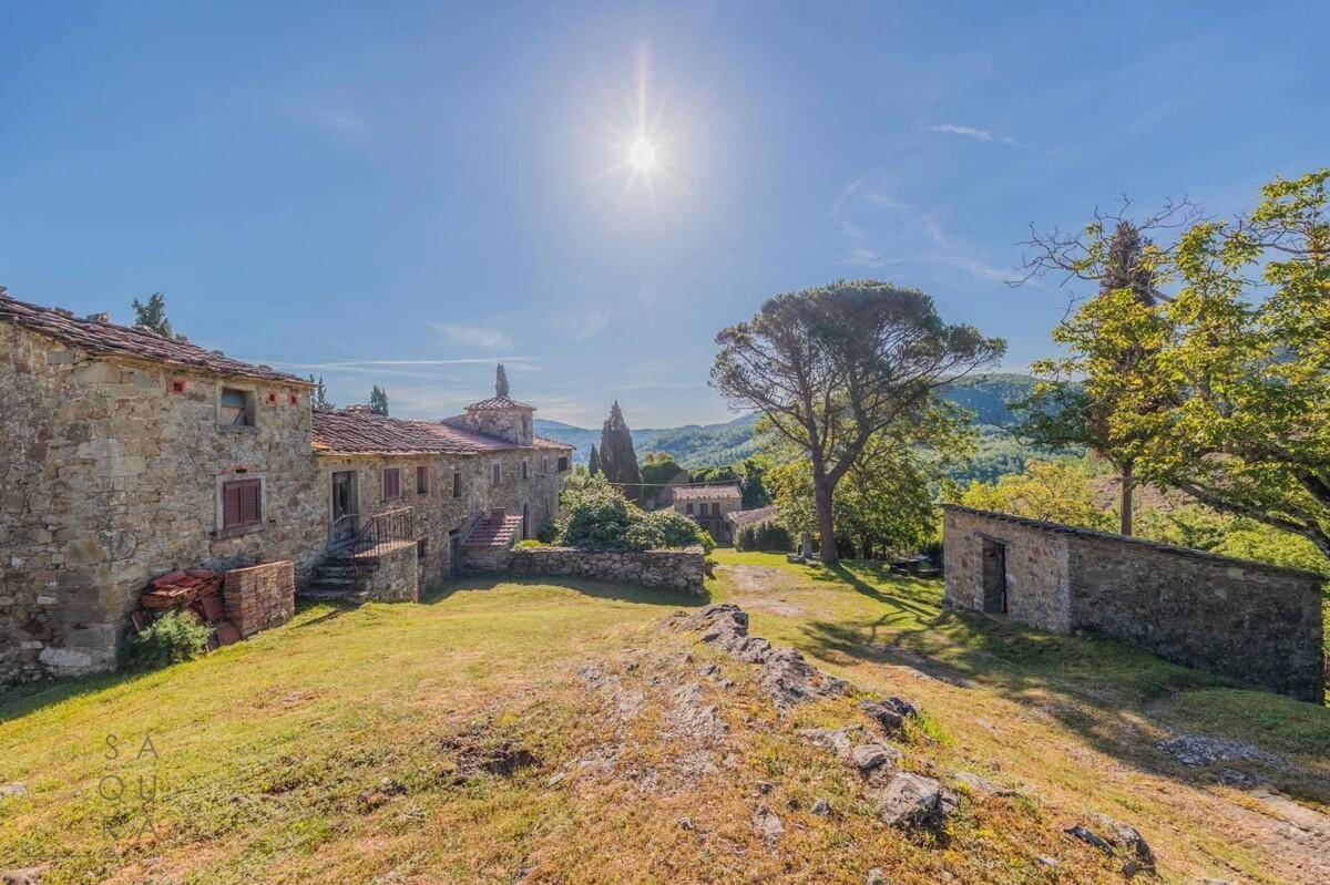 Weitläufiges Anwesen mit Steingebäuden und üppiger grüner Landschaft unter der Sommersonne.