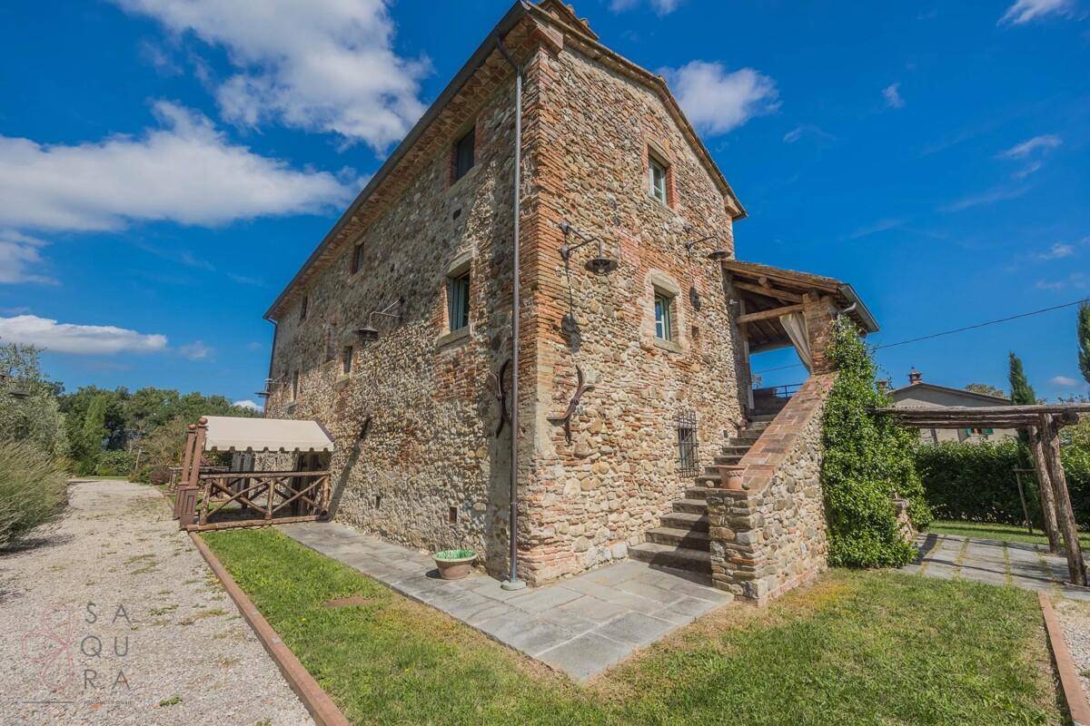Rustikales Landhaus mit Steinfassade, Außentreppe und einem charmanten überdachten Bereich.