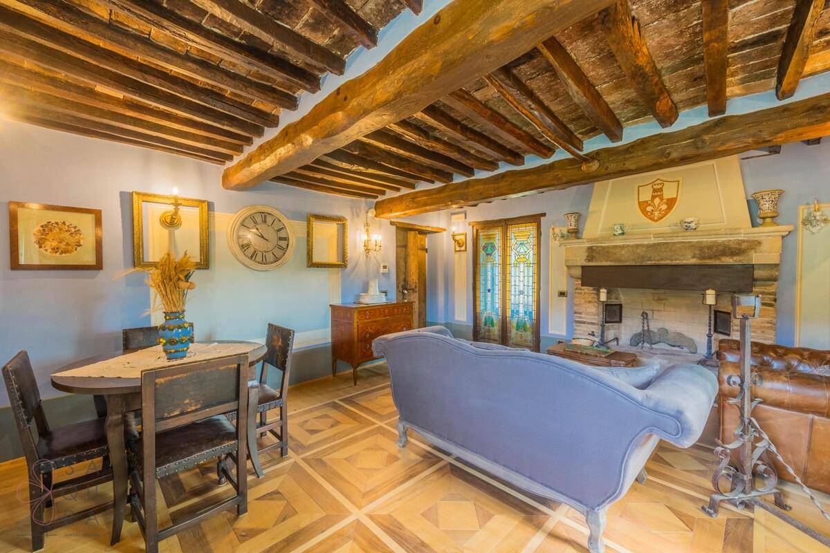 Traditionelles Wohnzimmer mit Holzbalken, großem Kamin und gemütlicher Sitzecke.