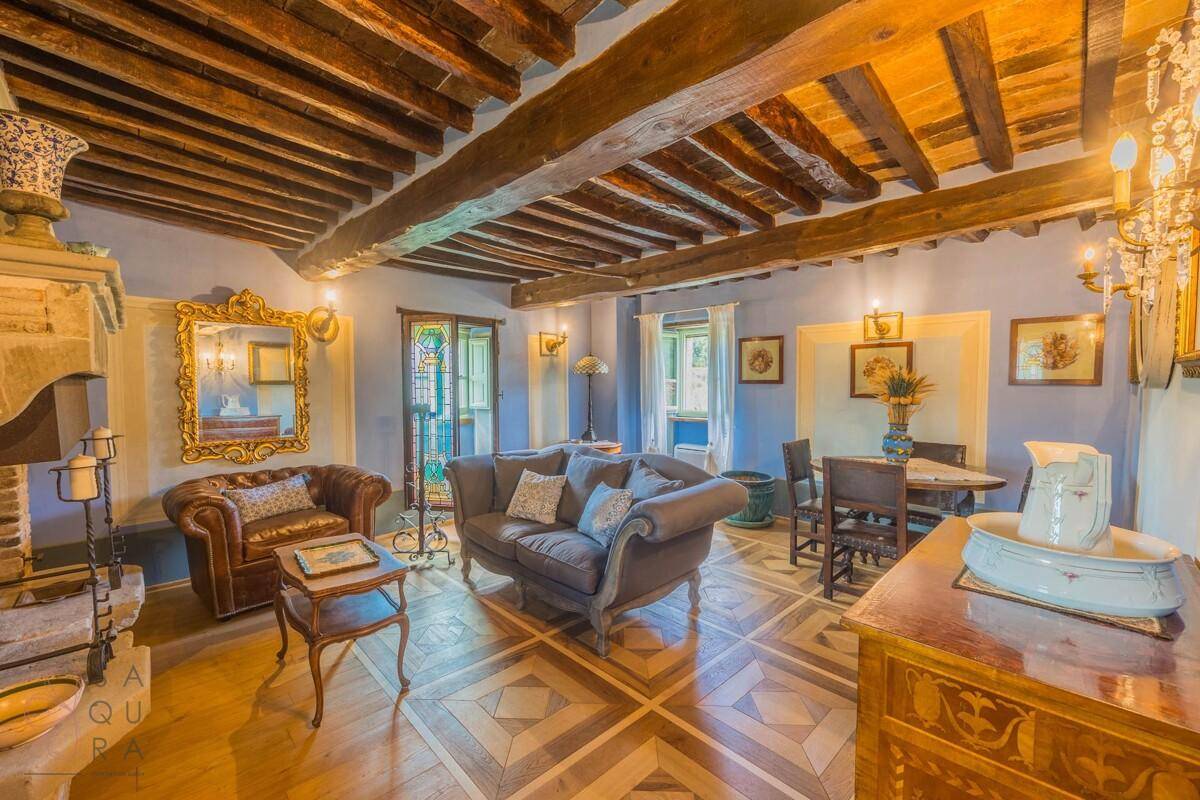 Geräumiges Wohnzimmer mit Holzbalkendecke, gemustertem Parkettboden und traditionellem Kamin.