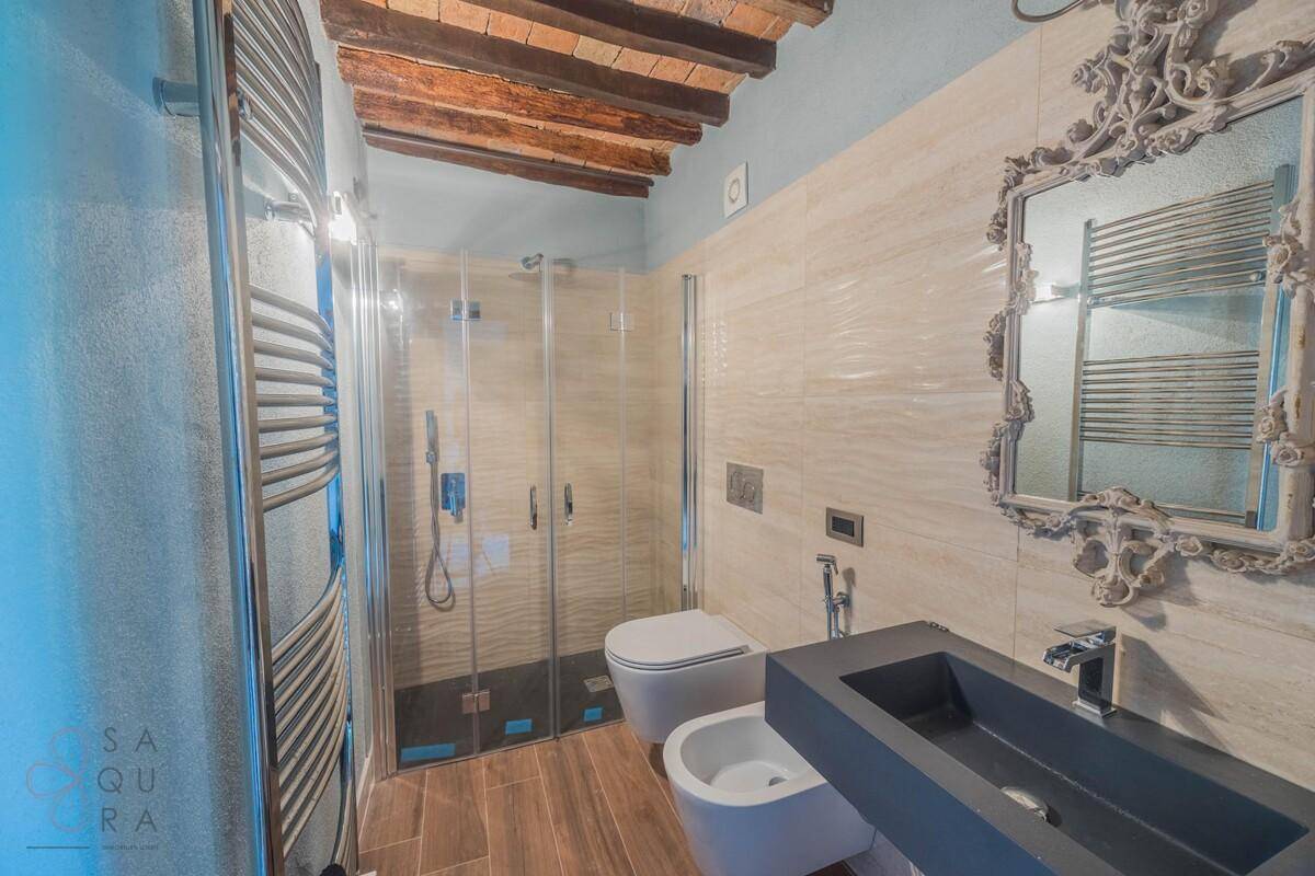 Modernes Badezimmer mit Dusche, Bidet, beheiztem Handtuchhalter und dunklem Waschbecken.
