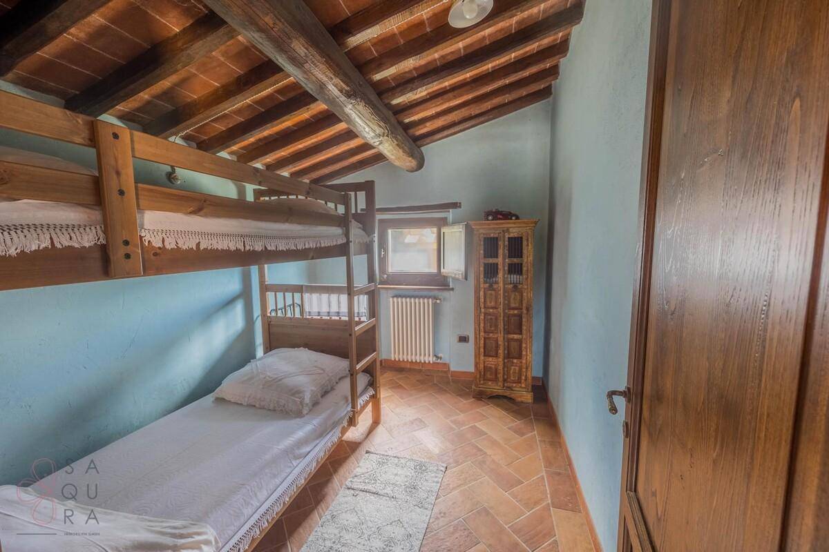 Kinderzimmer mit Etagenbett, Terrakottaboden und Holzbalkendecke.