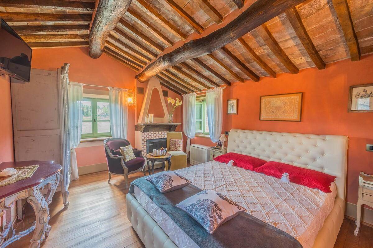 Gemütliches Schlafzimmer mit Holzbalken, Holzboden und Kamin.