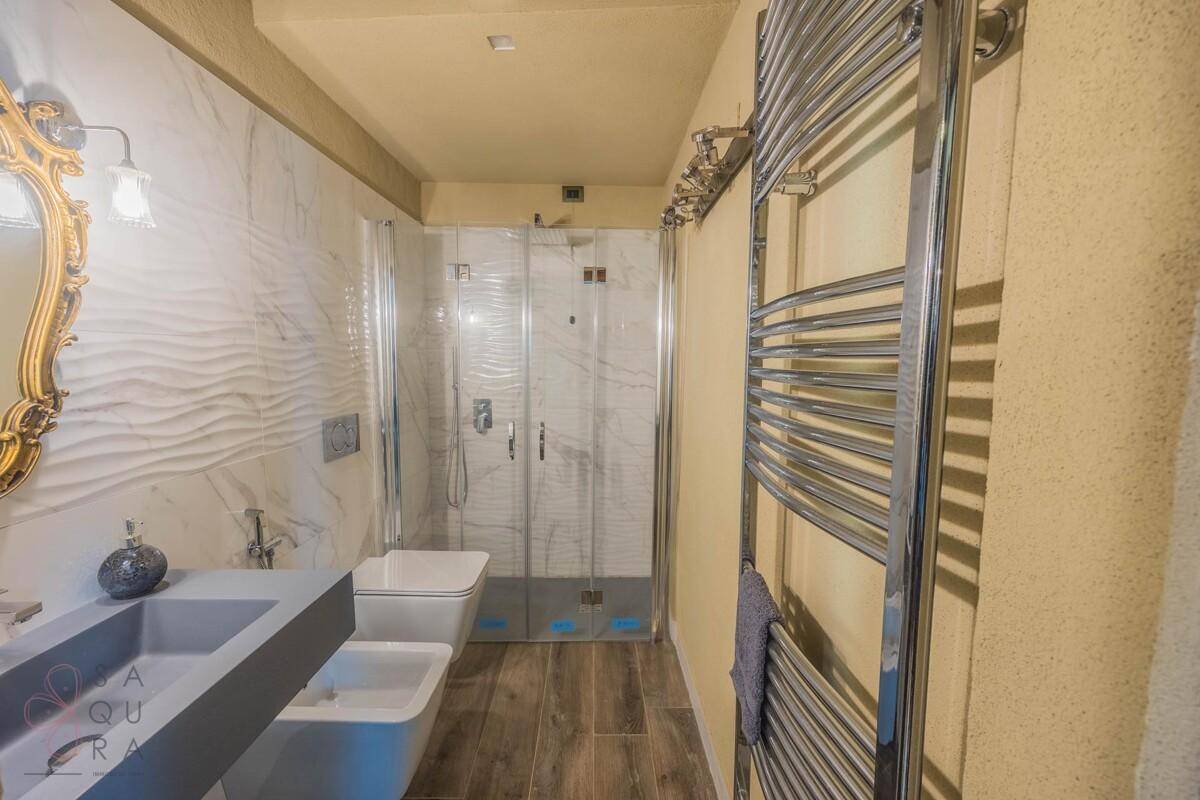 Helles Badezimmer mit Dusche, Bidet, beheiztem Handtuchhalter und modernem Waschbecken.