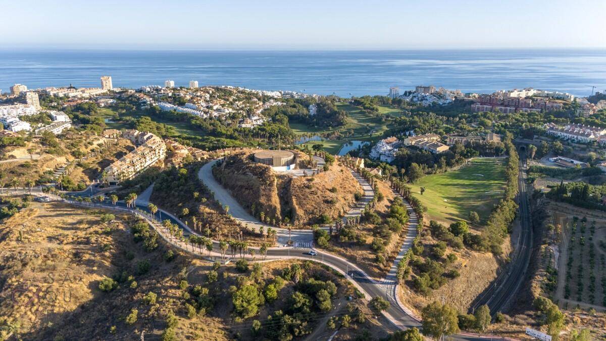 Panoramablick aus der Vogelperspektive auf eine Küstenlandschaft mit Golfplatz und Wohngebäuden am Meer.
