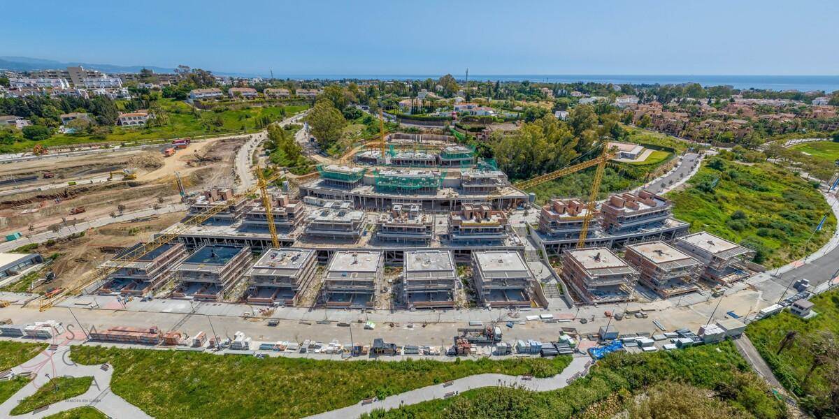 Luftaufnahme einer großen Wohnanlage im Bau mit Blick auf die Küste und das Meer.