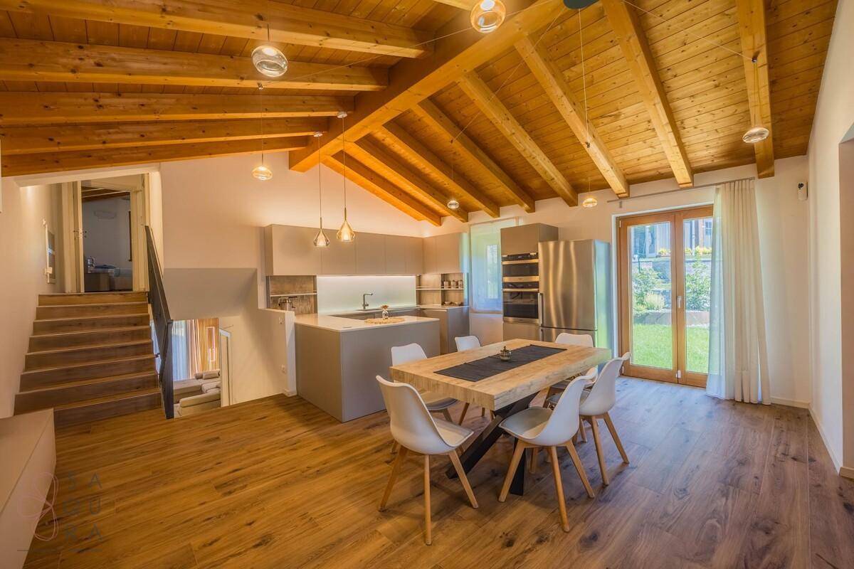 Heller offener Wohn-Essbereich mit moderner Küche, Holzbalkendecke und Gartenzugang.