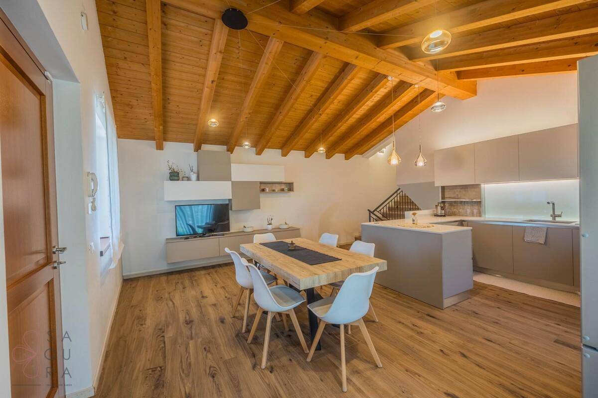 Geräumiger Wohn-Essbereich mit integrierter Küche, Holzbalkendecke und Holzfußboden.