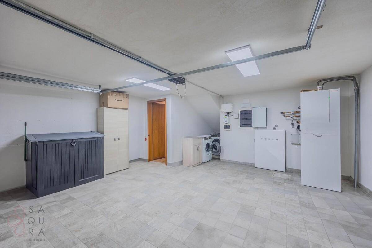 Großer Hauswirtschaftsraum mit Waschmaschine, Trockner und verschiedenen Lagermöglichkeiten.