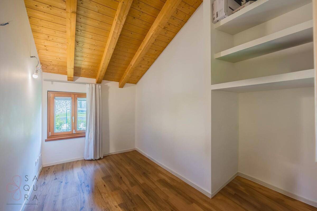 Helles Zimmer mit Holzbalkendecke, Holzfußboden und eingebauten Regalen.
