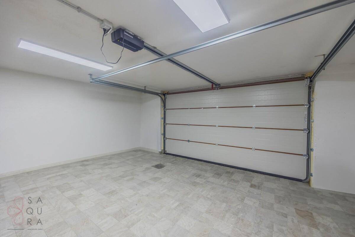 Geräumige Garage mit automatischem Tor und Fliesenboden.